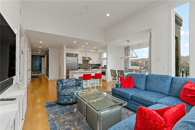 living room featuring light hardwood / wood-style floors, sink, and crown molding