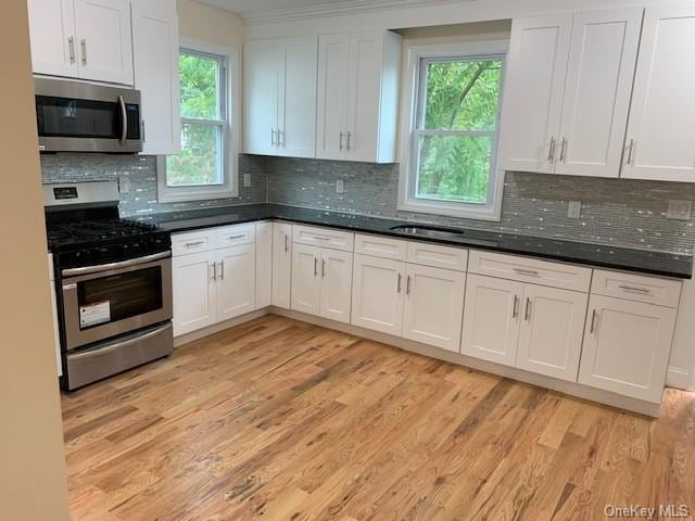 kitchen with decorative backsplash, white cabinetry, and stainless steel appliances