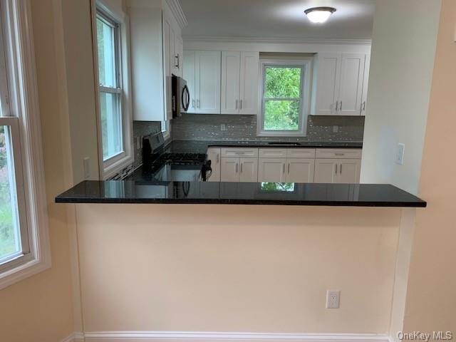 kitchen with white cabinets, black range with electric stovetop, kitchen peninsula, and tasteful backsplash