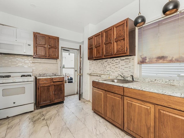 kitchen featuring backsplash, sink, pendant lighting, and white appliances