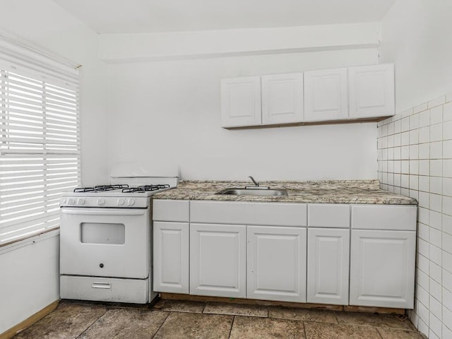 kitchen featuring white cabinets, tile walls, sink, and gas range gas stove