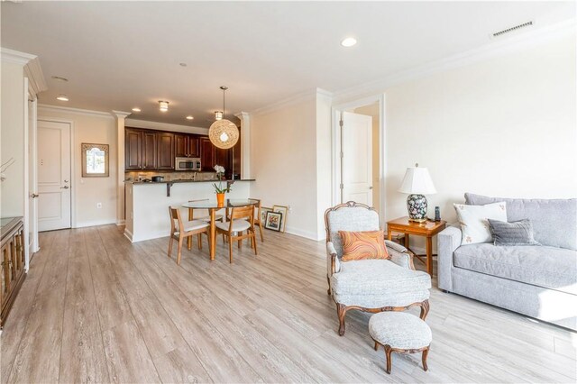 living room with crown molding and light hardwood / wood-style flooring