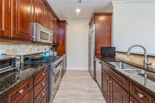 kitchen featuring sink, high end appliances, and dark stone countertops