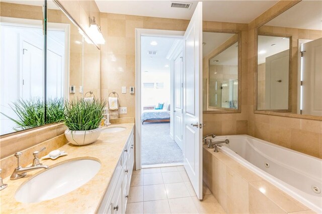 bathroom with tile patterned flooring, vanity, tile walls, and tiled tub