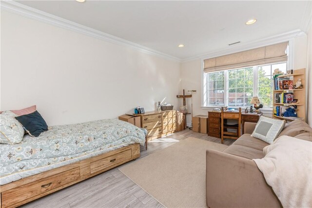 bedroom featuring ornamental molding and light hardwood / wood-style flooring