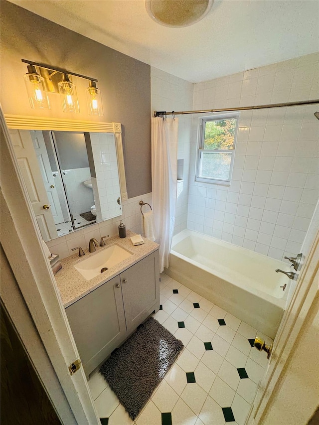 full bathroom with vanity, tile patterned floors, toilet, shower / bath combo with shower curtain, and tile walls