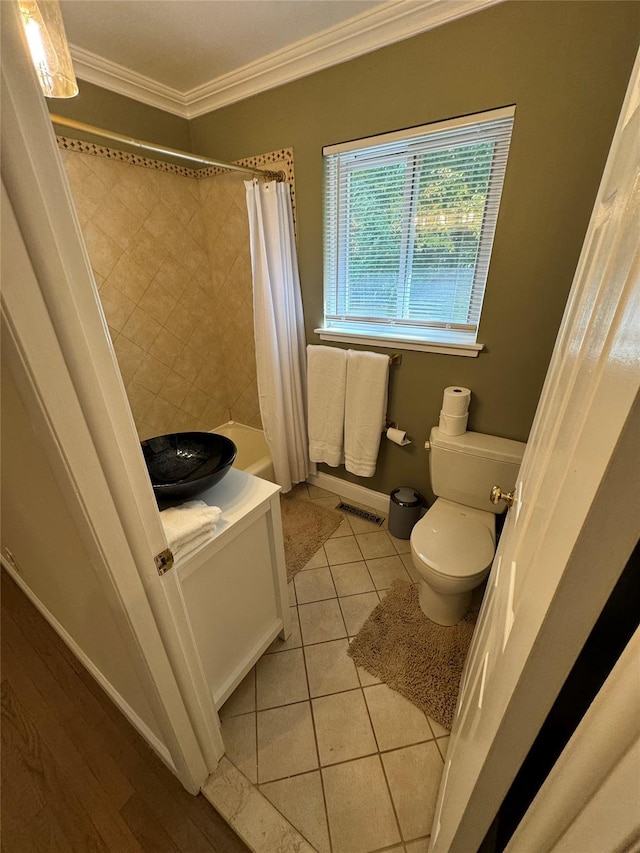 bathroom with tile patterned flooring, shower / bath combination with curtain, toilet, and crown molding