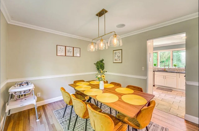 dining room with light wood-type flooring, ornamental molding, and sink