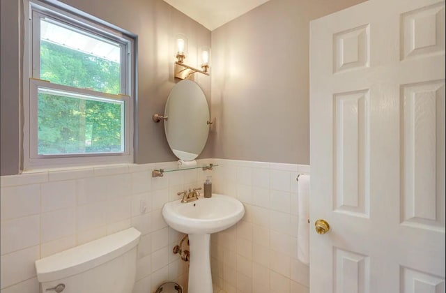 bathroom featuring toilet and tile walls