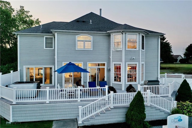 back house at dusk with a wooden deck