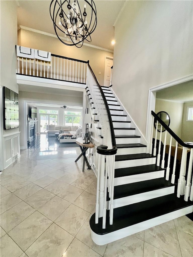 stairway with a chandelier, a towering ceiling, ornamental molding, and tile patterned flooring