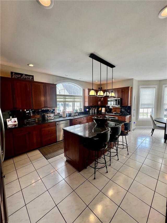 kitchen with a center island, decorative backsplash, decorative light fixtures, light tile patterned flooring, and stainless steel appliances