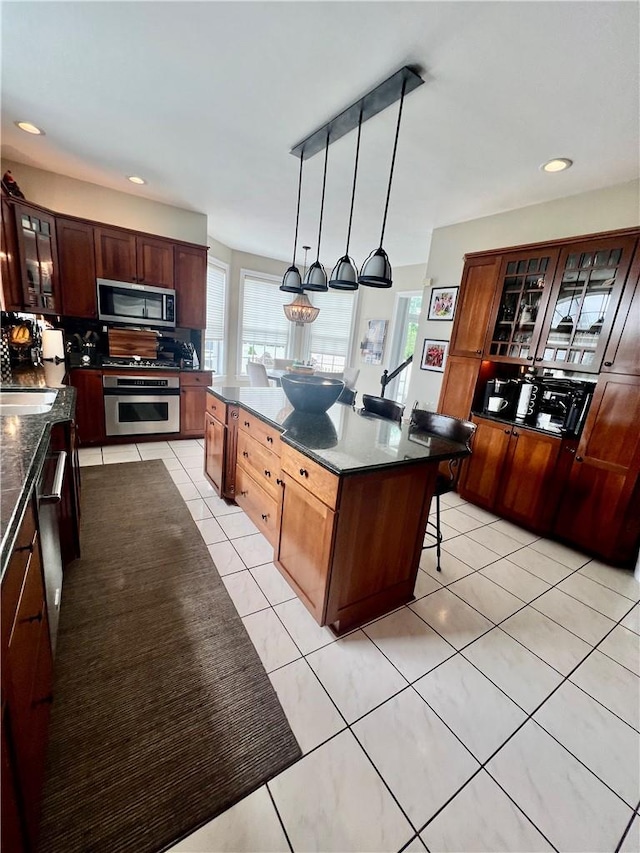 kitchen with plenty of natural light, a kitchen island, pendant lighting, and appliances with stainless steel finishes