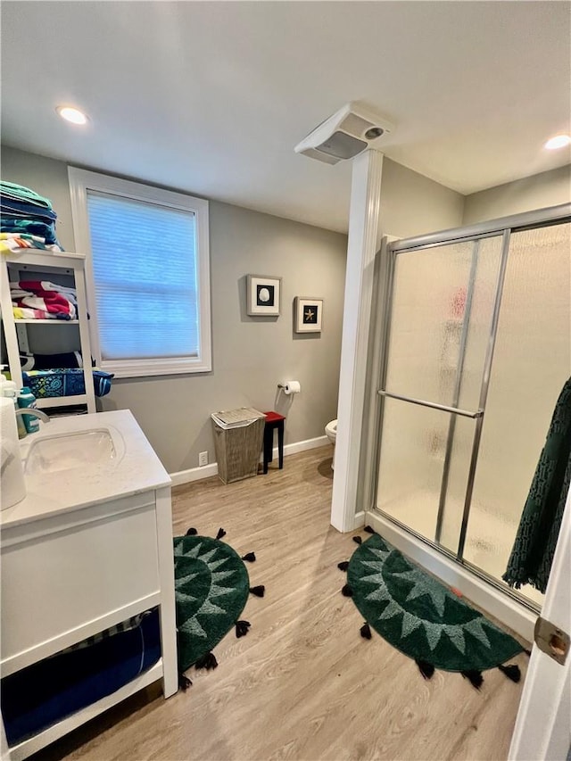 bathroom with vanity, toilet, wood-type flooring, and a shower with door