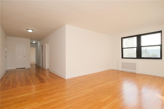 unfurnished room with light hardwood / wood-style floors and radiator heating unit