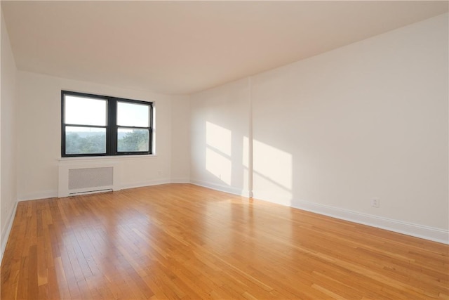 empty room with light hardwood / wood-style floors and radiator