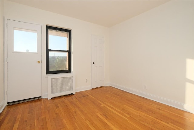 empty room featuring light wood-type flooring and radiator