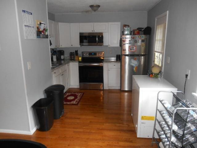 kitchen featuring kitchen peninsula, white cabinets, light wood-type flooring, and appliances with stainless steel finishes