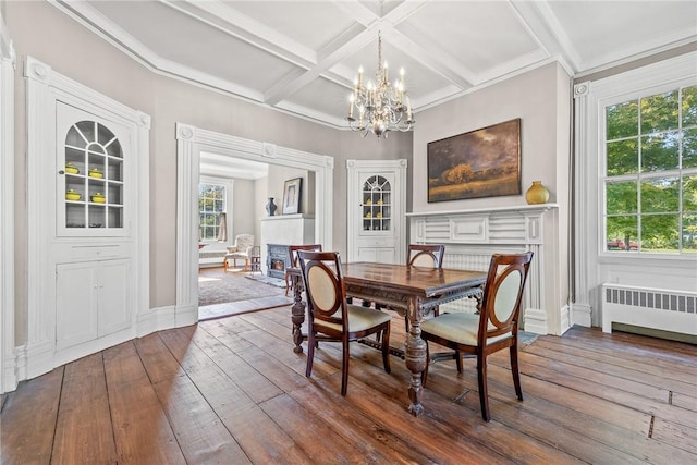 dining space featuring radiator, dark hardwood / wood-style floors, beamed ceiling, a chandelier, and coffered ceiling