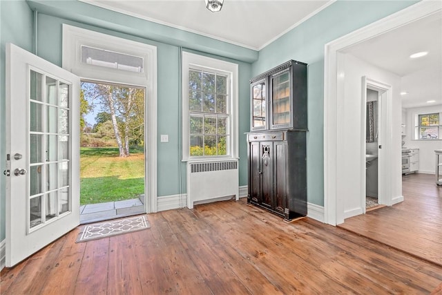 entryway featuring wood-type flooring, radiator heating unit, and crown molding