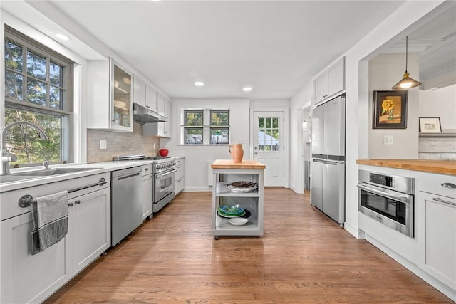 kitchen with sink, wooden counters, hanging light fixtures, stainless steel appliances, and white cabinets