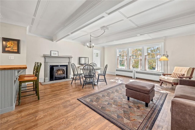 living room with hardwood / wood-style flooring, crown molding, radiator heating unit, and a notable chandelier