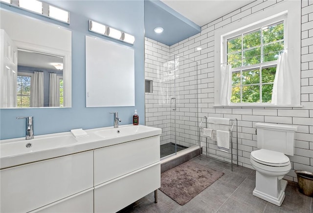 bathroom featuring toilet, tile walls, vanity, a shower with door, and tile patterned flooring