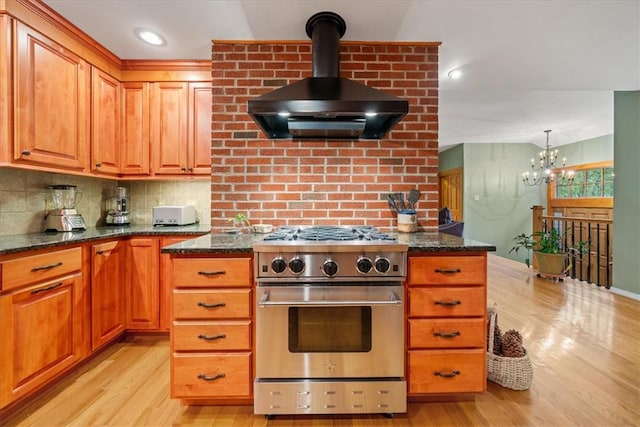 kitchen featuring island exhaust hood, dark stone counters, high end stainless steel range oven, and light wood-type flooring