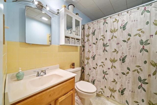 bathroom featuring walk in shower, vanity, toilet, and tile walls