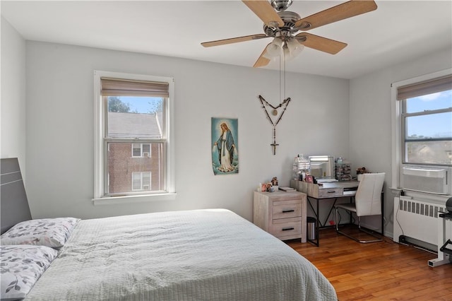 bedroom featuring hardwood / wood-style floors, ceiling fan, and radiator heating unit