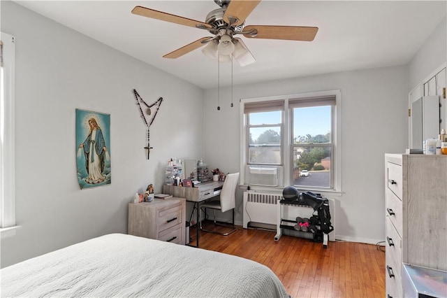 bedroom featuring ceiling fan, radiator heating unit, white refrigerator, and light wood-type flooring