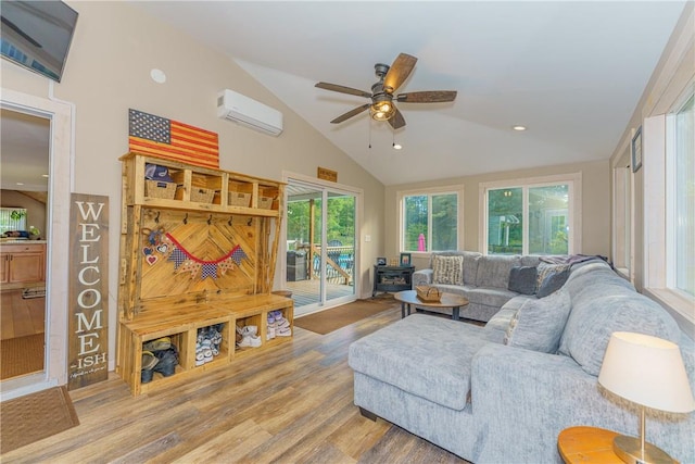 living room featuring a wood stove, ceiling fan, a wall unit AC, hardwood / wood-style floors, and vaulted ceiling