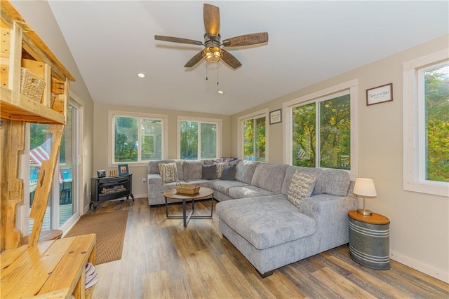 living room featuring hardwood / wood-style flooring, ceiling fan, lofted ceiling, and a wood stove