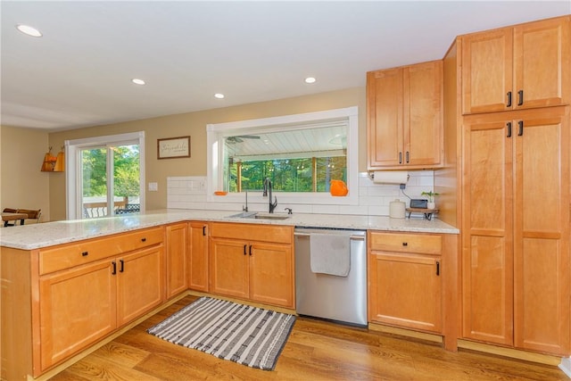 kitchen with sink, stainless steel dishwasher, tasteful backsplash, light hardwood / wood-style floors, and kitchen peninsula