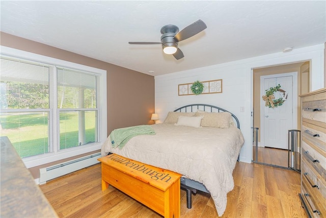 bedroom featuring ceiling fan, light hardwood / wood-style flooring, and a baseboard heating unit