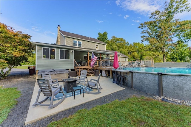 rear view of property featuring a fire pit and a pool side deck