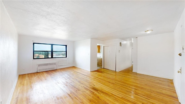 unfurnished room featuring light wood-type flooring and radiator