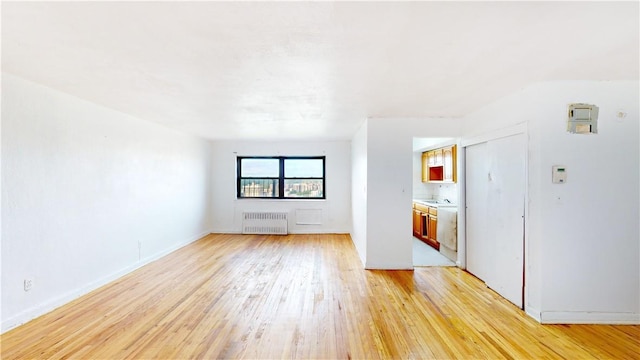 unfurnished living room with radiator heating unit and light wood-type flooring