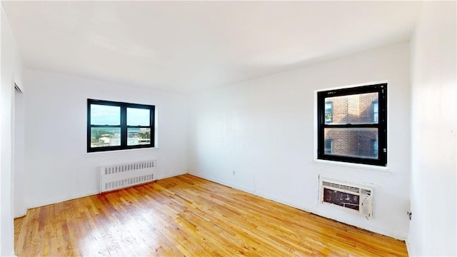 unfurnished room featuring hardwood / wood-style floors, radiator heating unit, and heating unit