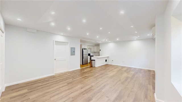 basement with stainless steel refrigerator, electric panel, and light wood-type flooring