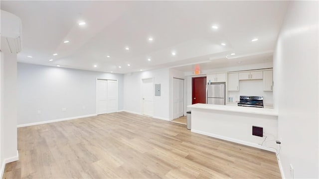 unfurnished living room with electric panel and light hardwood / wood-style floors