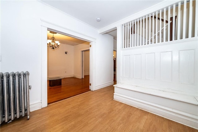 interior space featuring radiator, an inviting chandelier, ornamental molding, and hardwood / wood-style flooring