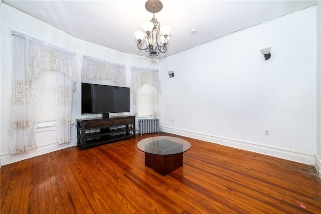 unfurnished living room with radiator heating unit, plenty of natural light, a notable chandelier, and hardwood / wood-style floors