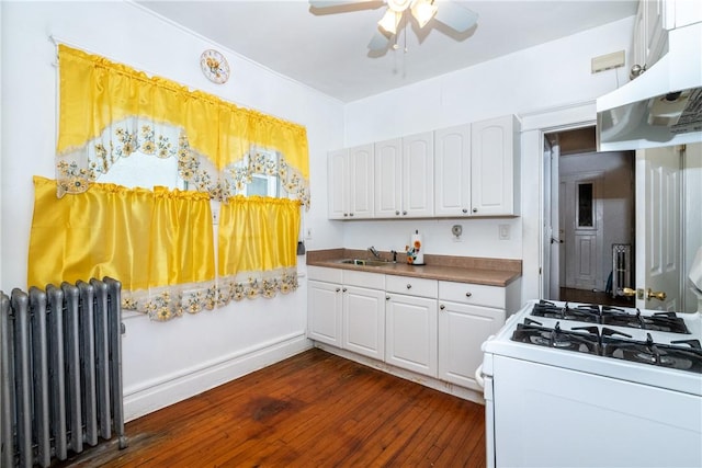 kitchen with dark hardwood / wood-style flooring, white gas range, radiator, sink, and white cabinets