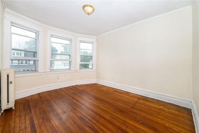 spare room featuring radiator, crown molding, a healthy amount of sunlight, and hardwood / wood-style flooring