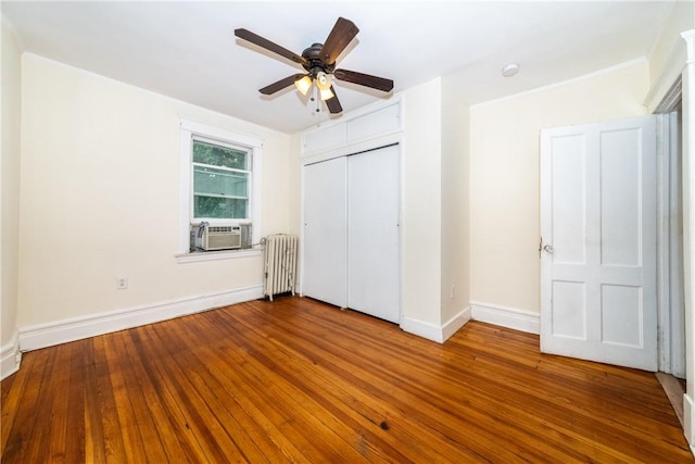 unfurnished bedroom with ceiling fan, wood-type flooring, radiator, and a closet