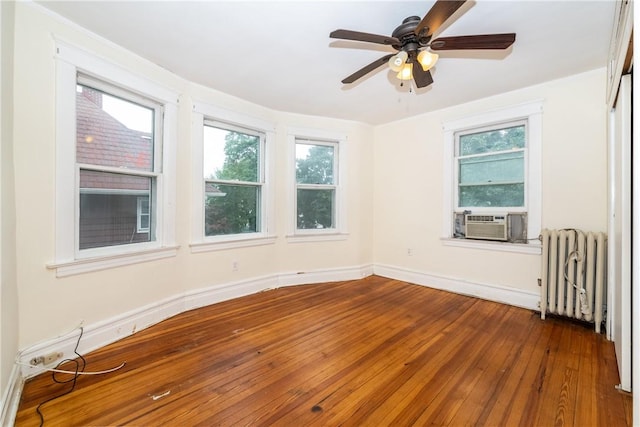 unfurnished room featuring ceiling fan, radiator heating unit, cooling unit, and wood-type flooring