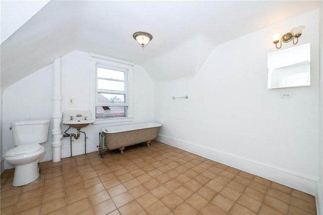 bathroom with toilet, tile patterned floors, vaulted ceiling, and a tub