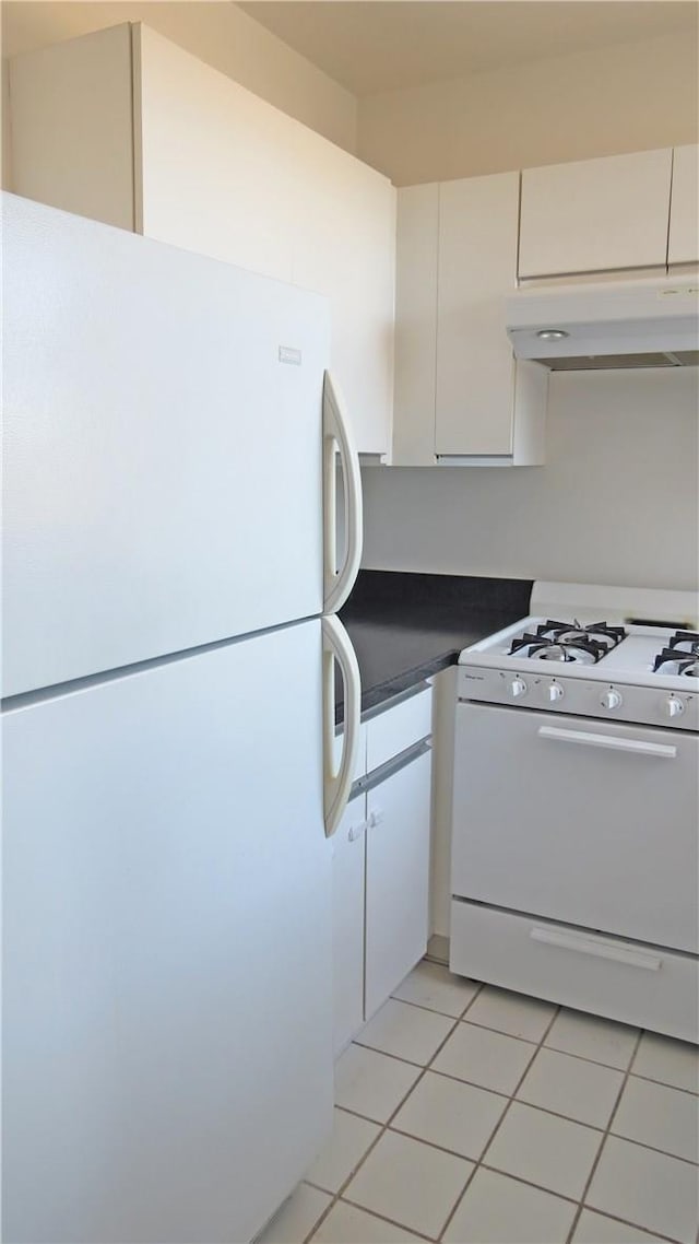 kitchen with white appliances, white cabinetry, and light tile patterned flooring