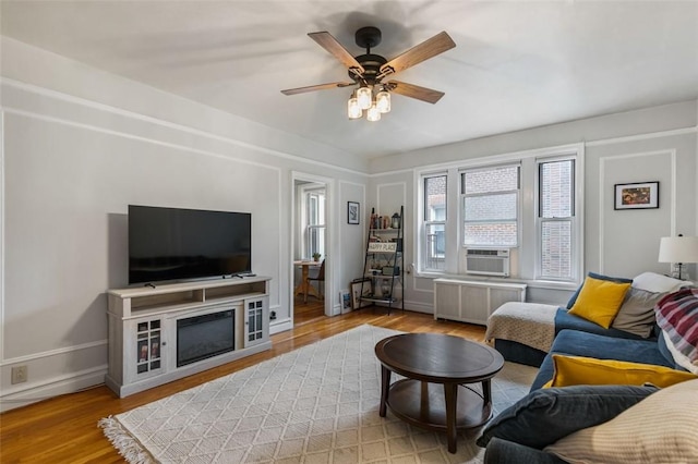 living room featuring radiator heating unit, light hardwood / wood-style flooring, ceiling fan, and cooling unit